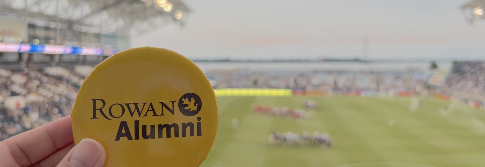 A Rowan University Alumni button in front of a Philadelphia Union game.