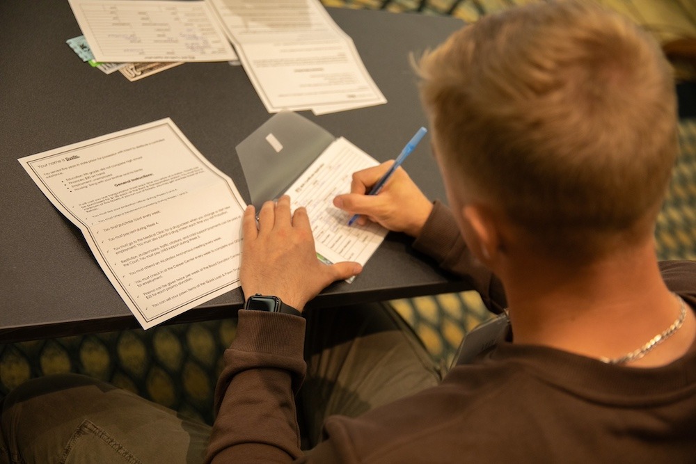 A law and justice student fills out an application card using his assigned identity sheet as a guide.