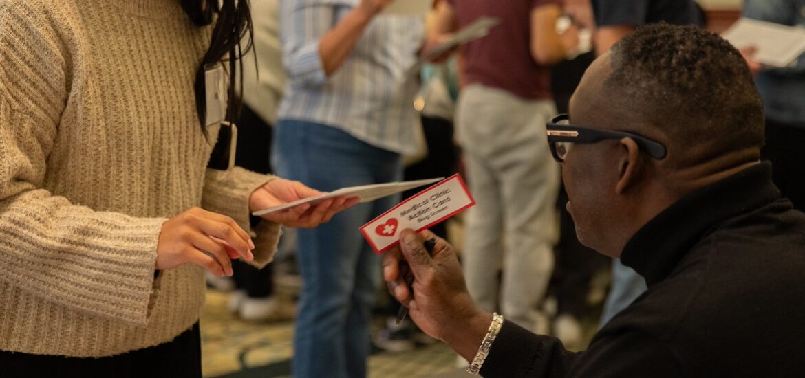 A close up of a man at a table handing a law and justice student a card that says medical clinic access card.