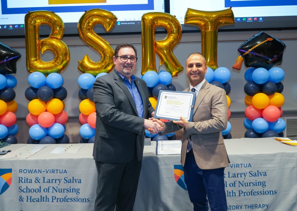 RRT to BSRT candidate smiling at program pinning celebration with certificate in hand.