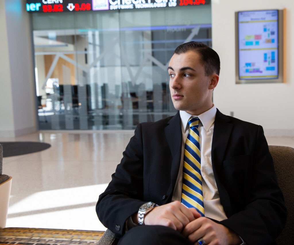 Man in a suit sitting confidently in a modern business setting, representing personal branding after earning an online MBA.