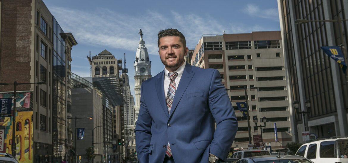 Professional graduate with a data analytics degree standing in Philadelphia business district.