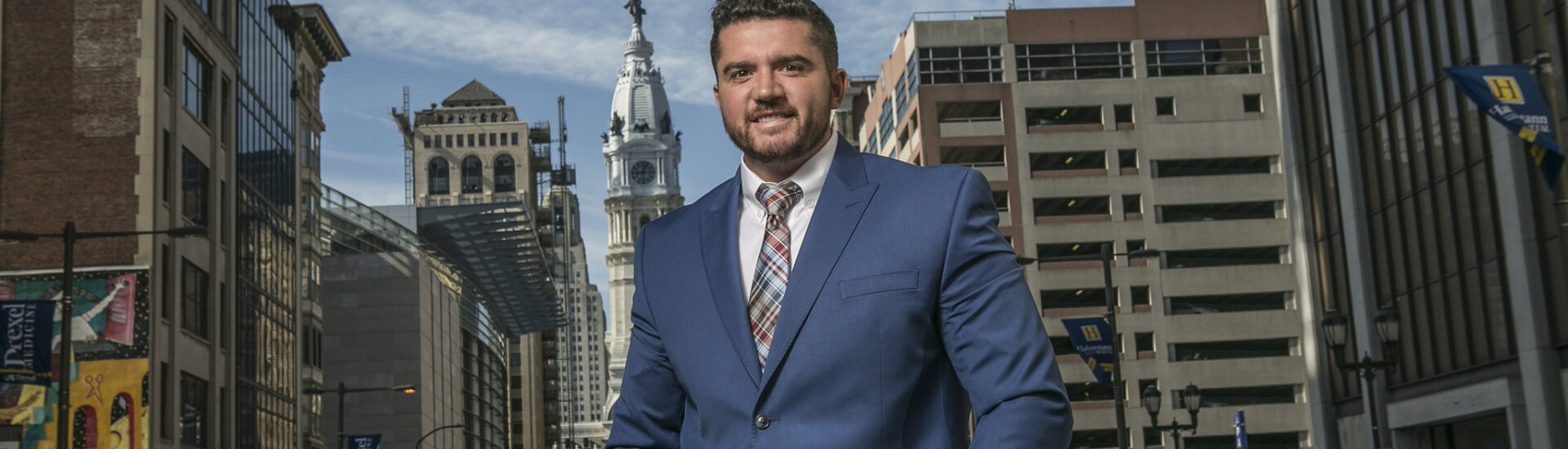 Professional graduate with a data analytics degree standing in Philadelphia business district.