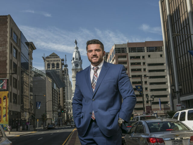Professional graduate with a data analytics degree standing in Philadelphia business district.