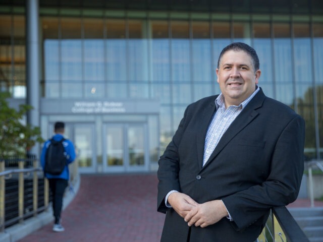 Rowan University business professional in front of the Rohrer College of Business, representing accredited online MBA programs.
