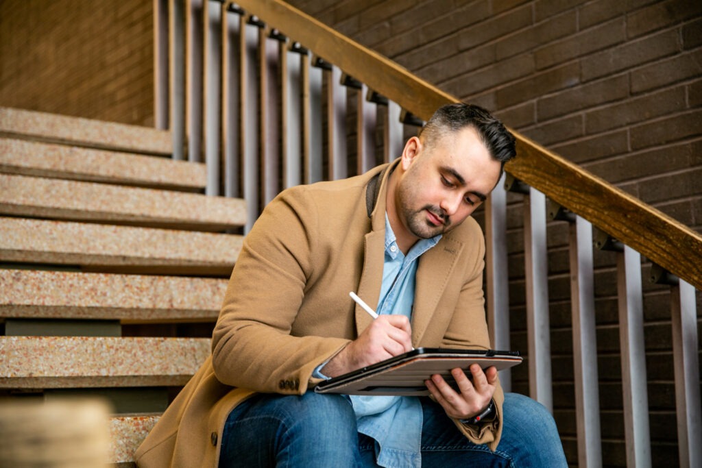 Adult learner taking online college notes on a tablet at Rowan University.