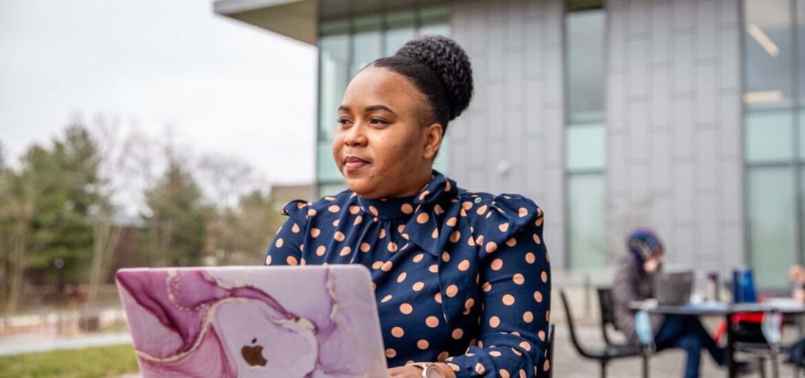 Online MBA student studying outdoors on Rowan University’s campus with a laptop.