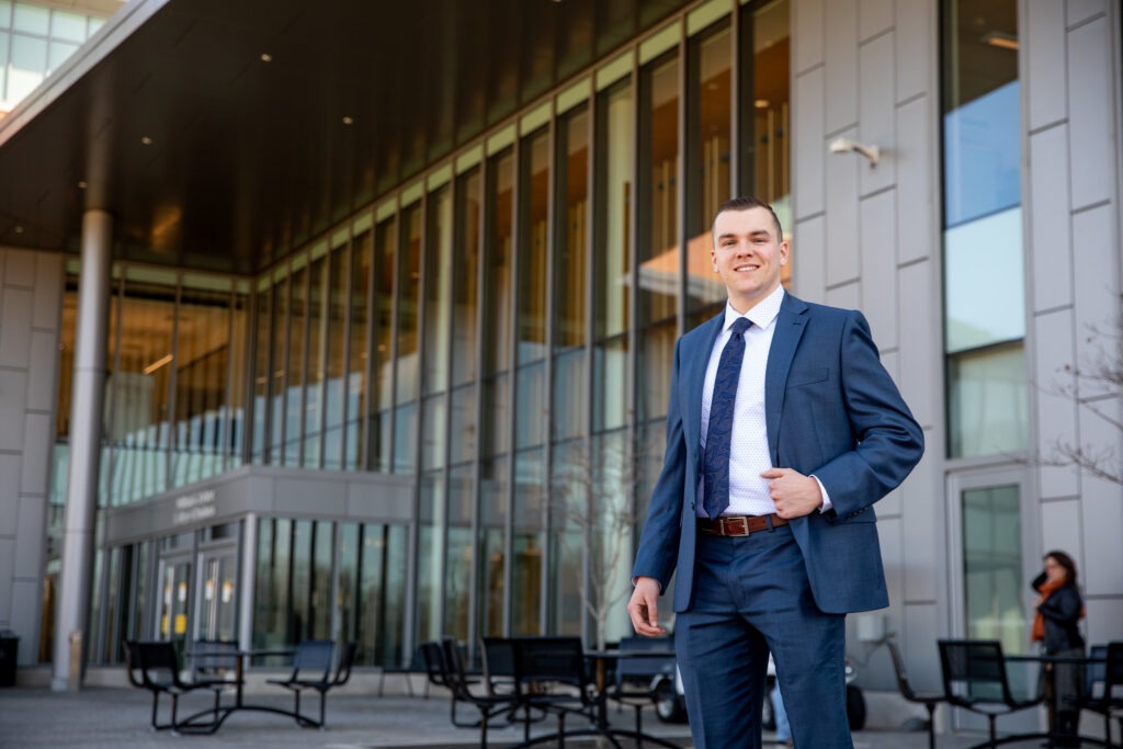 Online MBA student in a suit walking outside Rowan University’s business school.