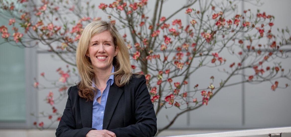 Smiling businesswoman in professional attire standing outdoors, representing leadership and career growth through an online MBA.