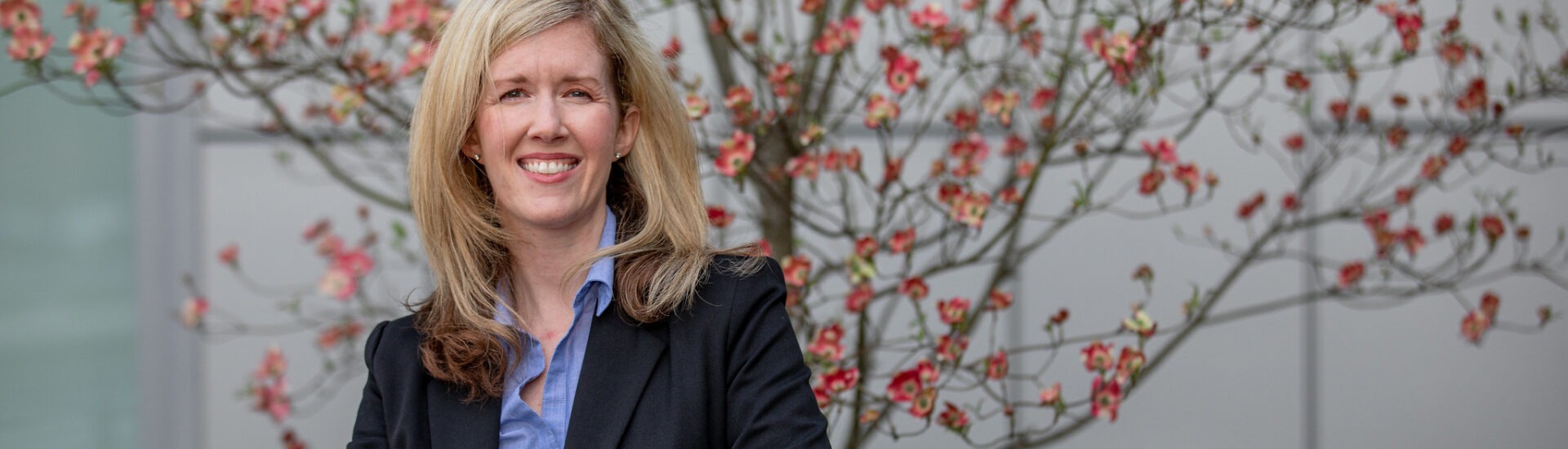 Smiling businesswoman in professional attire standing outdoors, representing leadership and career growth through an online MBA.