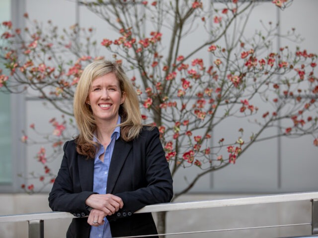 Smiling businesswoman in professional attire standing outdoors, representing leadership and career growth through an online MBA.