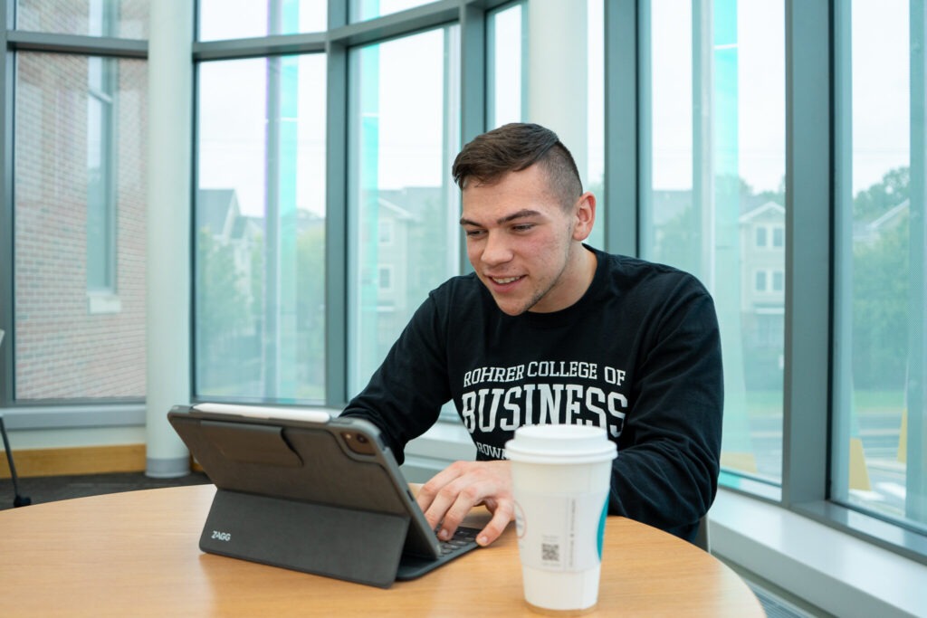 Online MBA student completing program coursework on tablet.