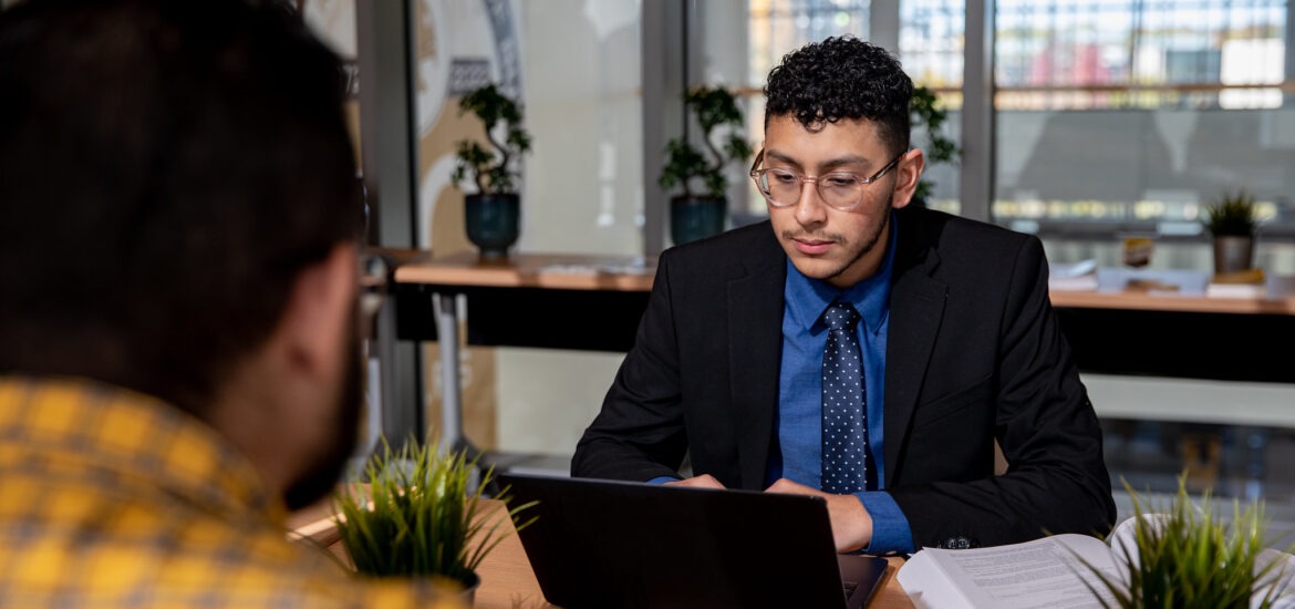 Man in business attire working on a laptop during a meeting, symbolizing professional growth with an MBA degree.