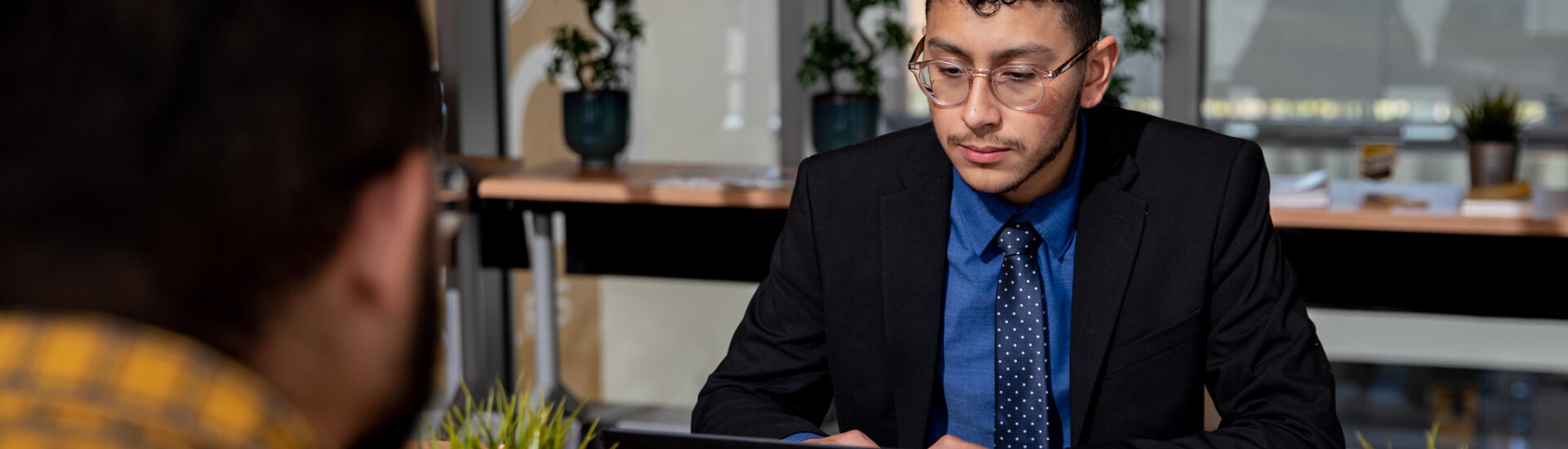 Man in business attire working on a laptop during a meeting, symbolizing professional growth with an MBA degree.