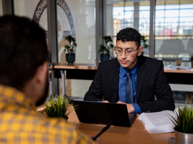 Man in business attire working on a laptop during a meeting, symbolizing professional growth with an MBA degree.