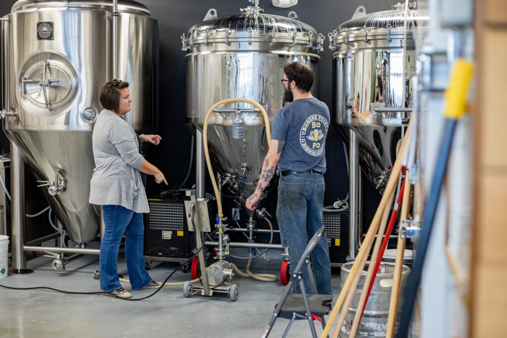 Two professionals discussing operations at a brewery facility, showing supply chain and business management in action with an MBA.
