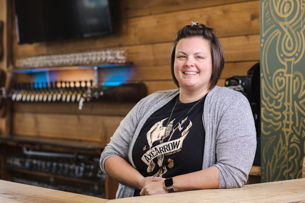 Female manager smiling at a brewery bar, showcasing leadership in small business management.