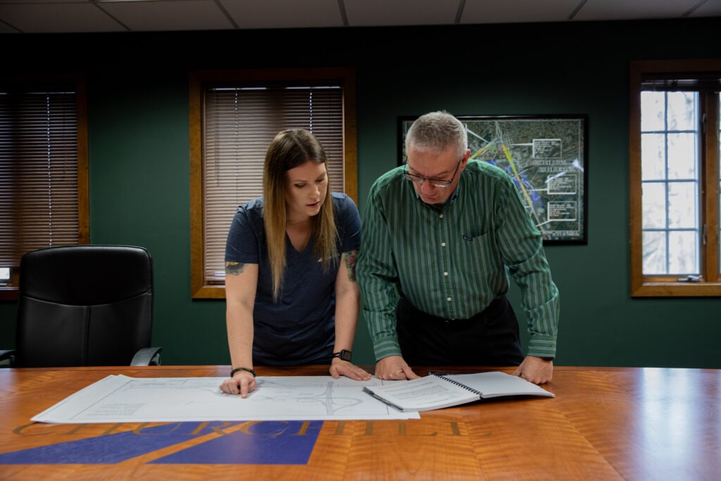 Construction manager and colleague reviewing blueprints together in an office meeting room.