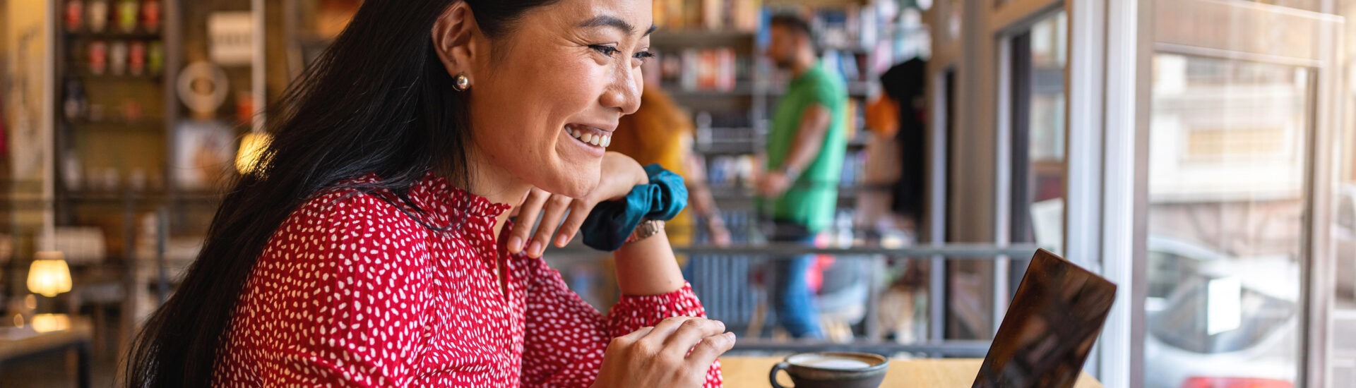 Student sitting in a coffee shop on her laptop completing work for her online courses.