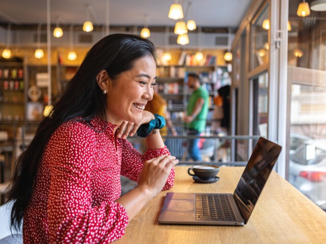 Student sitting in a coffee shop on her laptop completing work for her online courses.