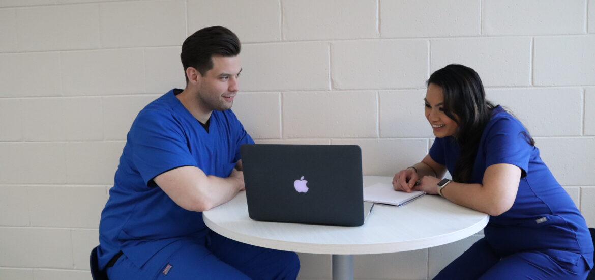 Two students enrolled in an RRT to BSRT program sitting at a table completing online coursework.