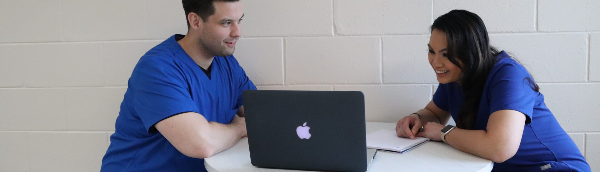 Two students enrolled in an RRT to BSRT program sitting at a table completing online coursework.