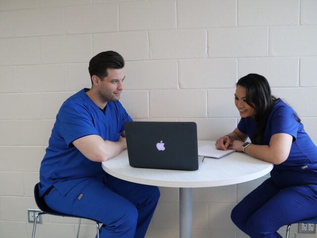 Two students enrolled in an RRT to BSRT program sitting at a table completing online coursework.