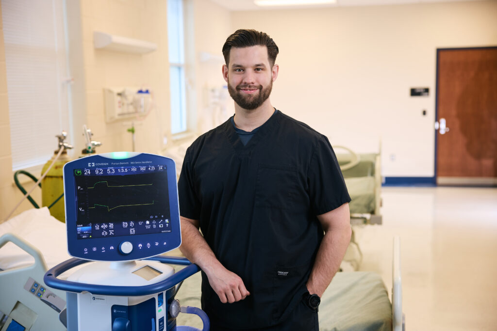 Jeff Porch, BSRT, RRT-ACCS, CPFT, standing beside respiratory care equipment, representing his career advancement as a BSRT program graduate.