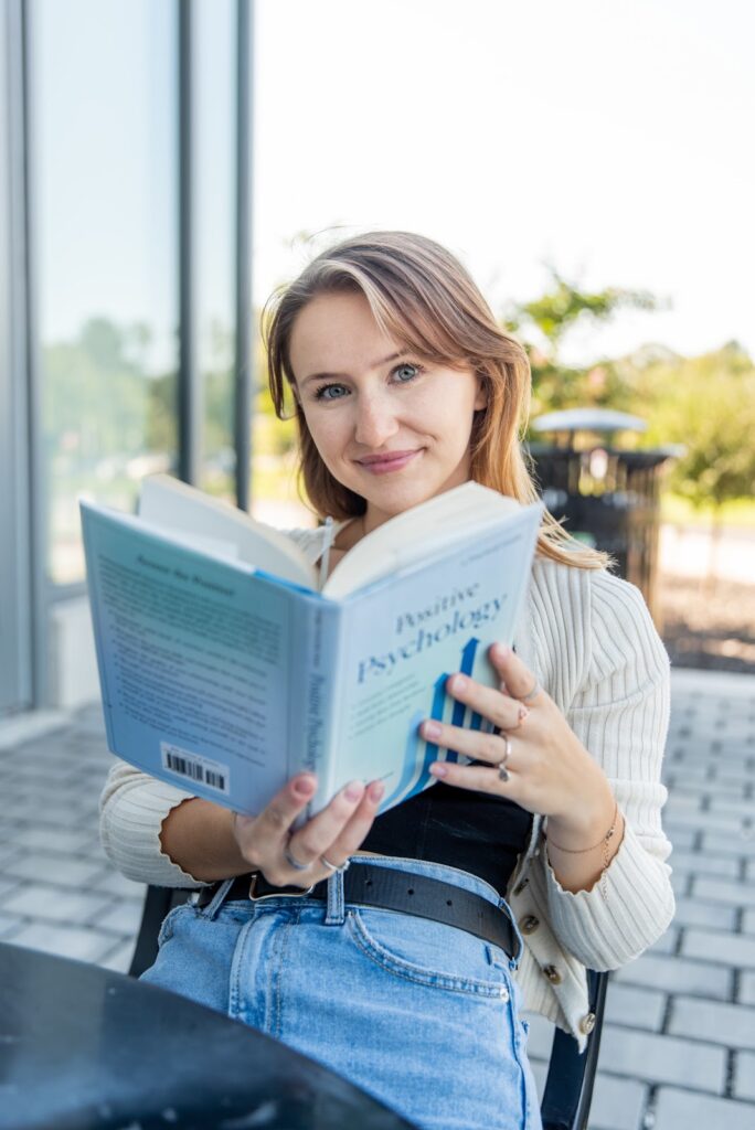 Student reading a Positive Psychology book outdoors, highlighting lifelong skills and growth from a psychology online degree.