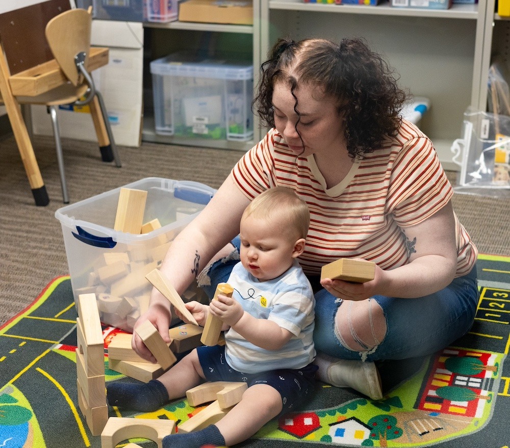 Psychology student supporting child development through play, showing social service career paths after a psychology online degree.