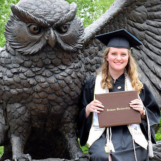 Rowan University online MBA graduate Victoria I. celebrating in cap and gown with diploma.