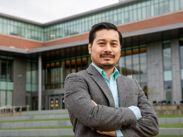 Confident professional standing outside a business school, representing the career opportunities with a Master of Business Administration (MBA).