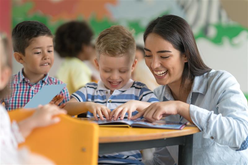Teacher who completed her certificate in early childhood special education working with a young child in the classroom.