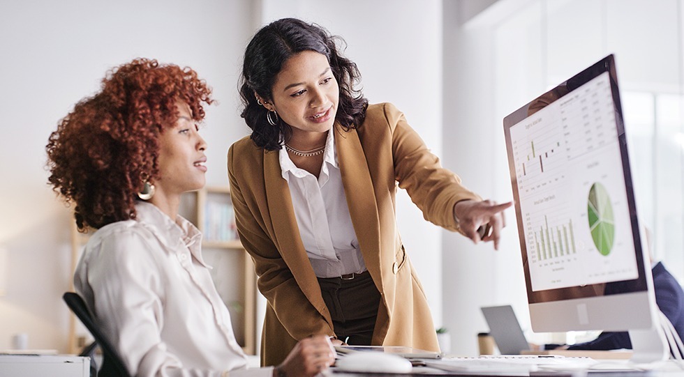 Two professionals analyzing data visualizations on a computer screen, applying data analytics skills to business decision-making.