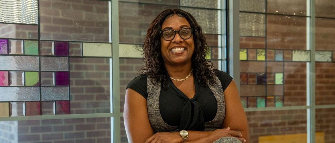 Online M.Ed. in Teacher Leadership student sitting down smiling with arms folded.