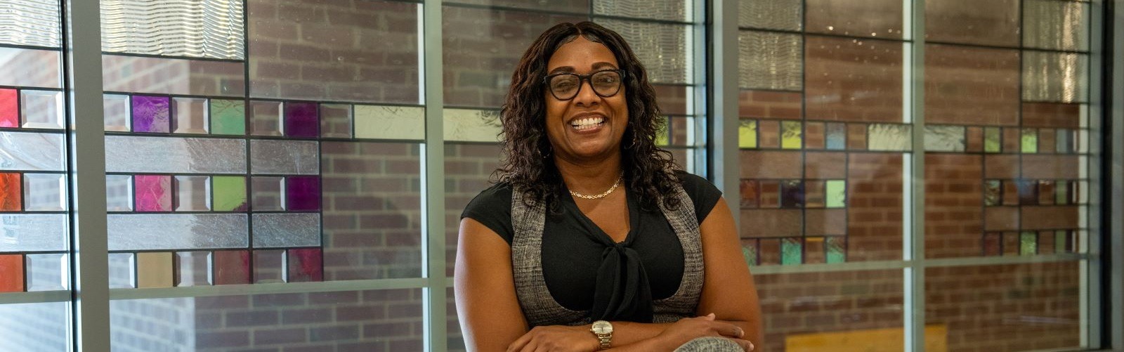 Online M.Ed. in Teacher Leadership student sitting down smiling with arms folded.