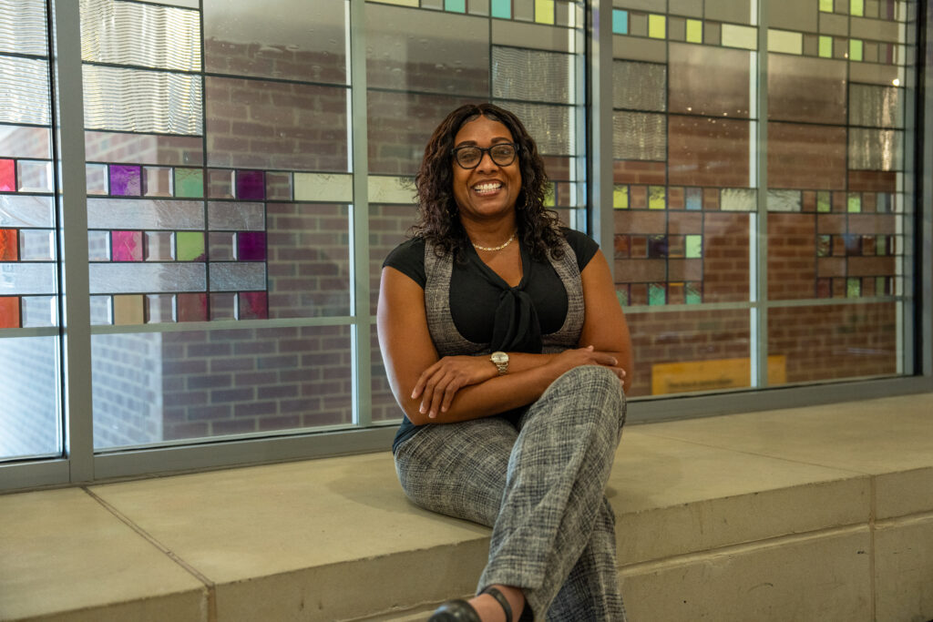 Online M.Ed. in Teacher Leadership student sitting down smiling with arms folded.