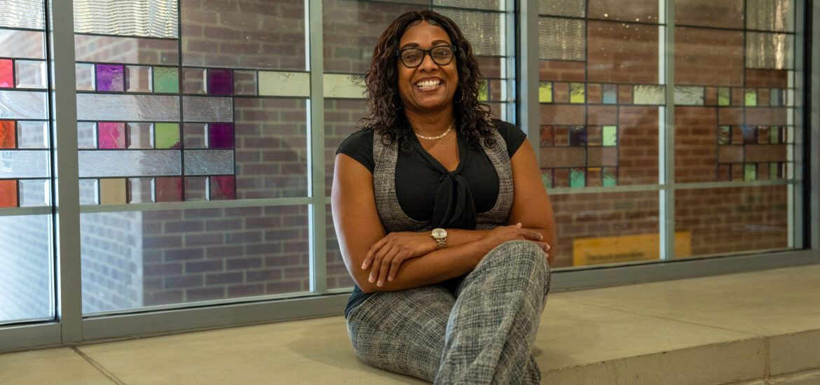 Online M.Ed. in Teacher Leadership student sitting down smiling with arms folded.