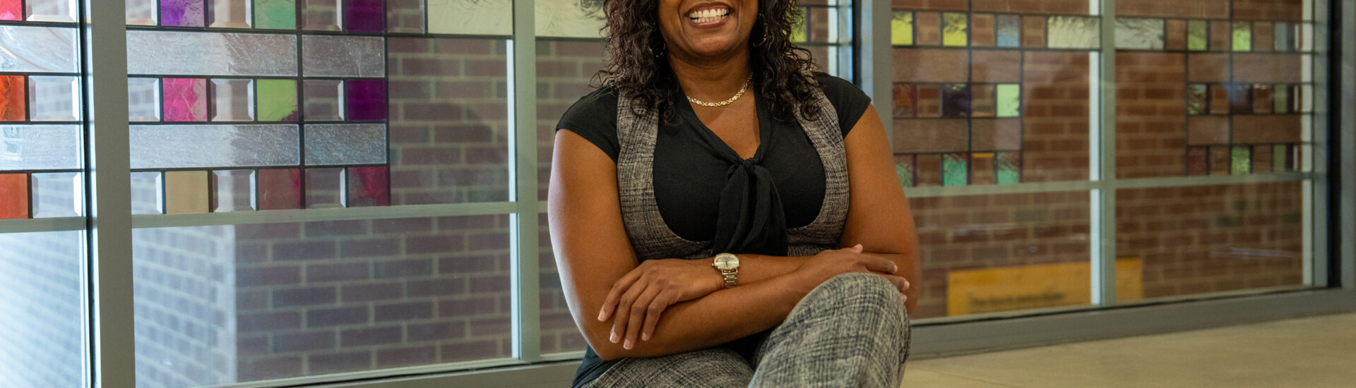 Online M.Ed. in Teacher Leadership student sitting down smiling with arms folded.
