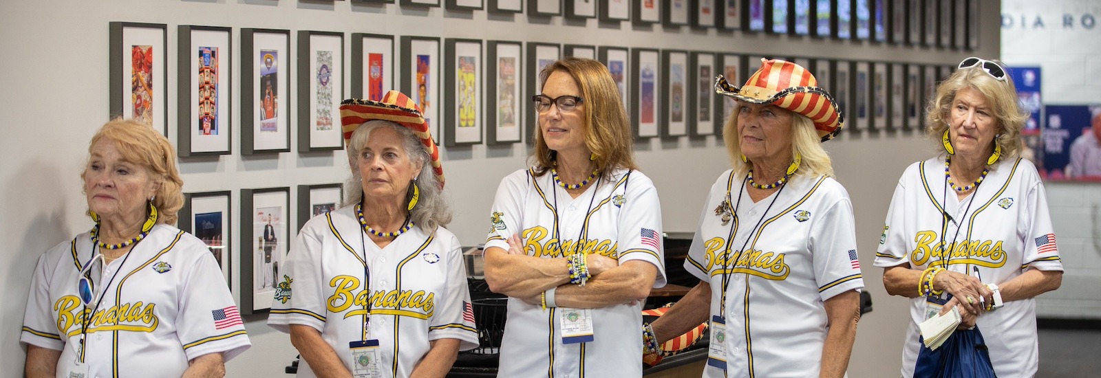 Five Banana Nanas stand shoulder to shoulder listening to a speaker before their performance.