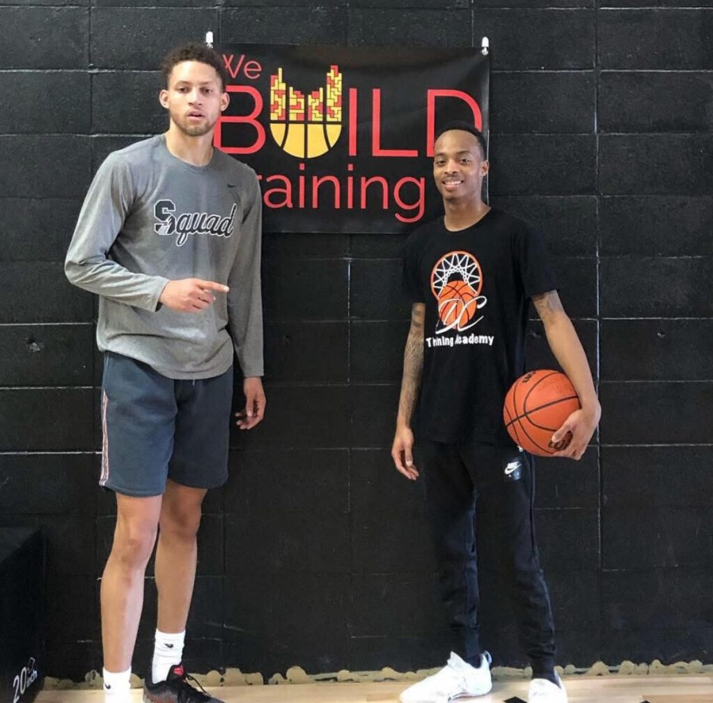 Devón holds a basketball while standing next to one of his basketball players. 