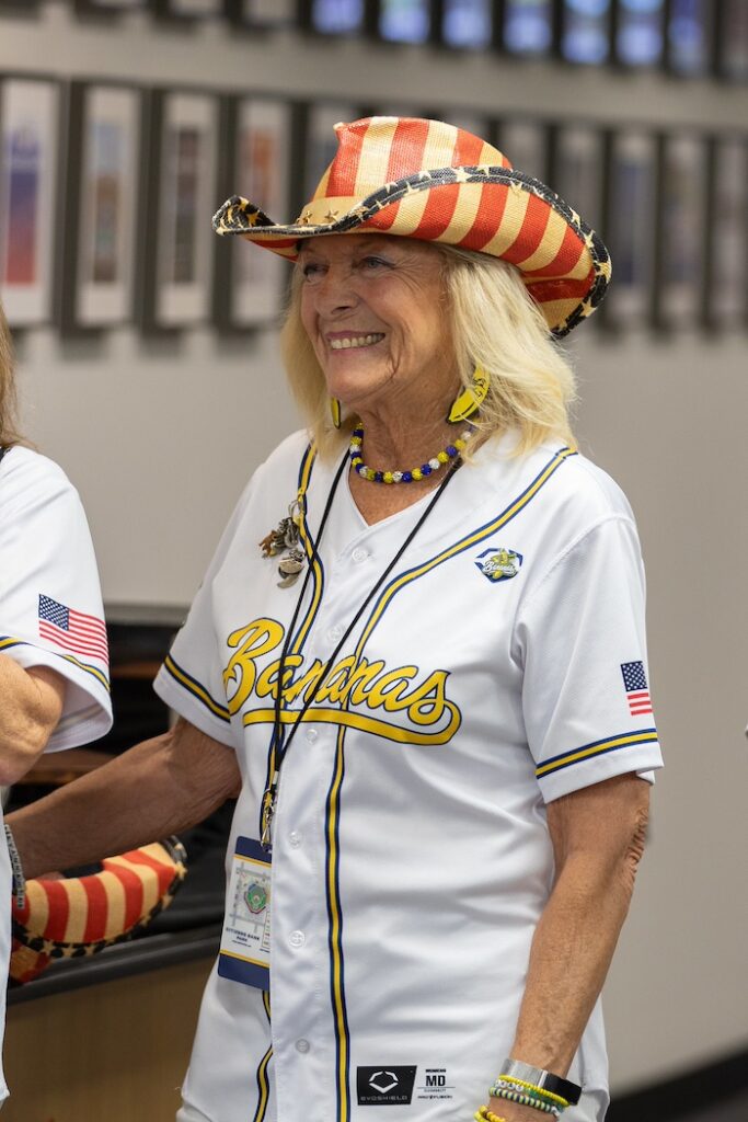 A portrait of Nana Karen, wearing a white and yellow Banana Nanas uniform and red white and blue cowboy hat. 