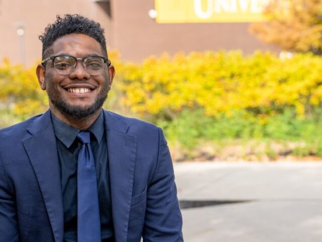 Shawn B. smiles outside Rowan University, representing connection and community in Rowan’s online Ed.D. in Educational Leadership program.