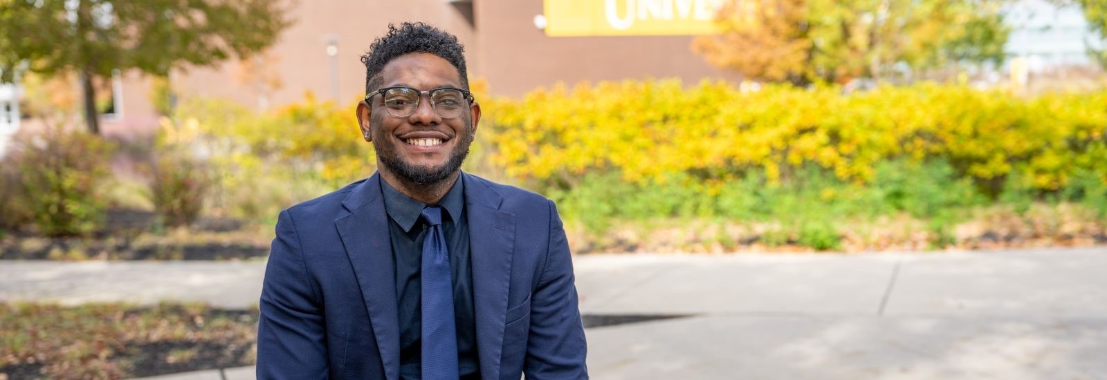 Shawn B. smiles outside Rowan University, representing connection and community in Rowan’s online Ed.D. in Educational Leadership program.