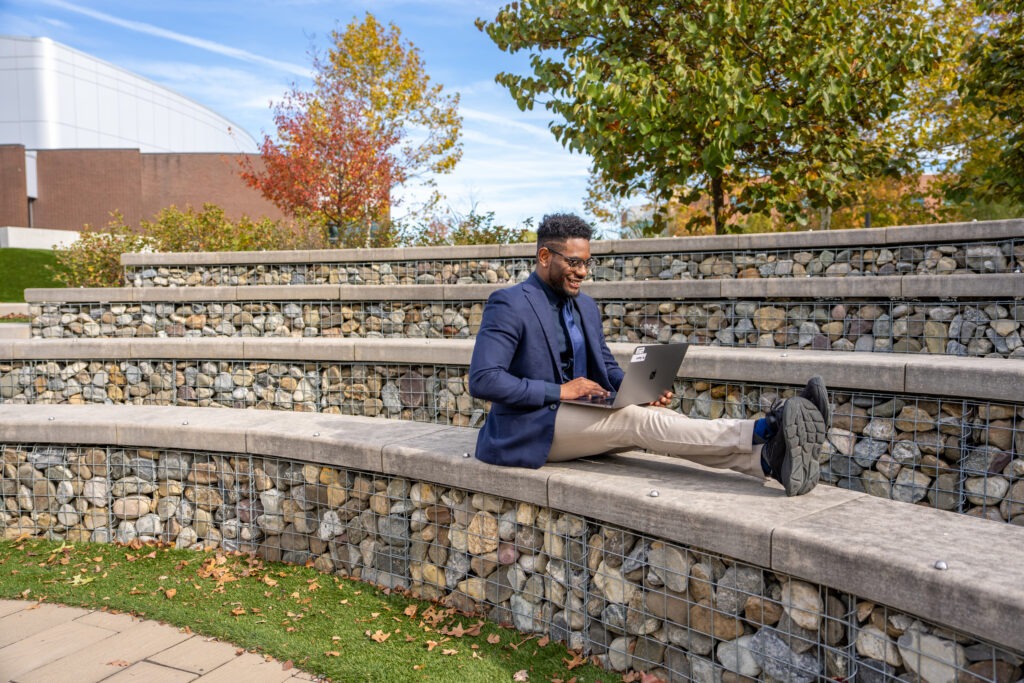 Shawn B. works on his laptop outdoors at Rowan University, representing the flexibility of Rowan’s fully online Ed.D. in Educational Leadership program.