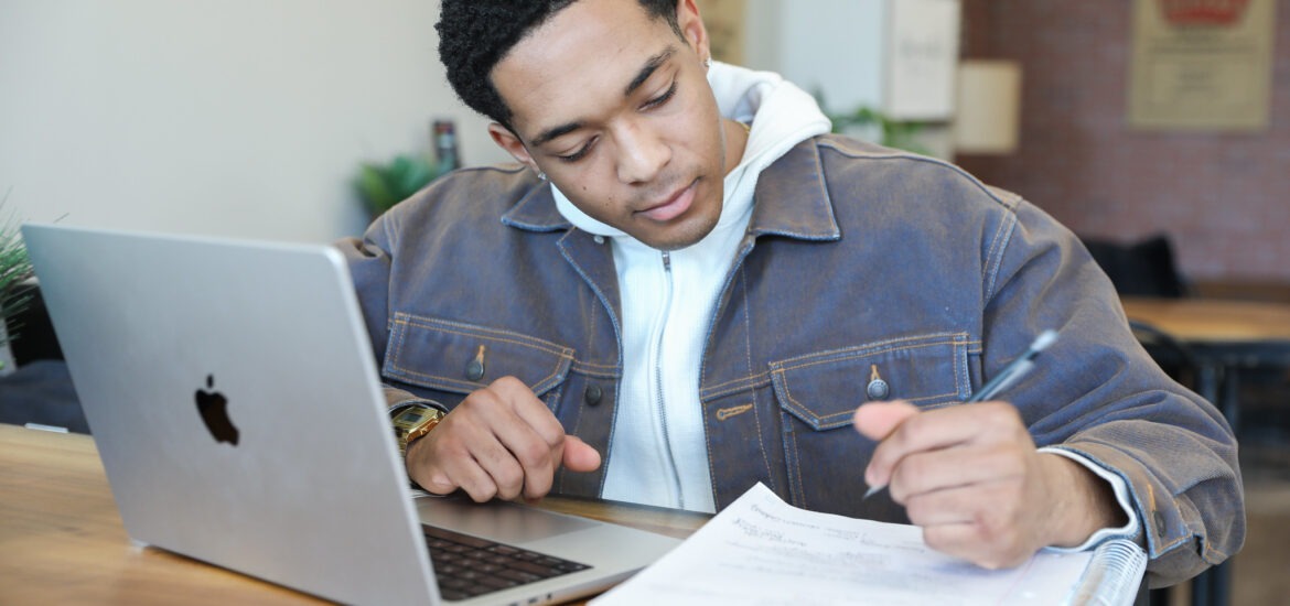 Student completing coursework for a winter course on laptop at a coffee shop.