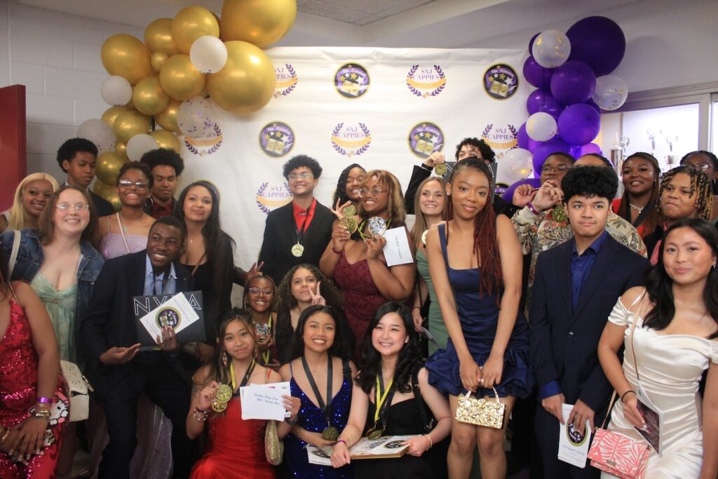26 excited and dressed up Winslow Township High School students pose together in front of a back drop for the Southern New Jersey Cappies.