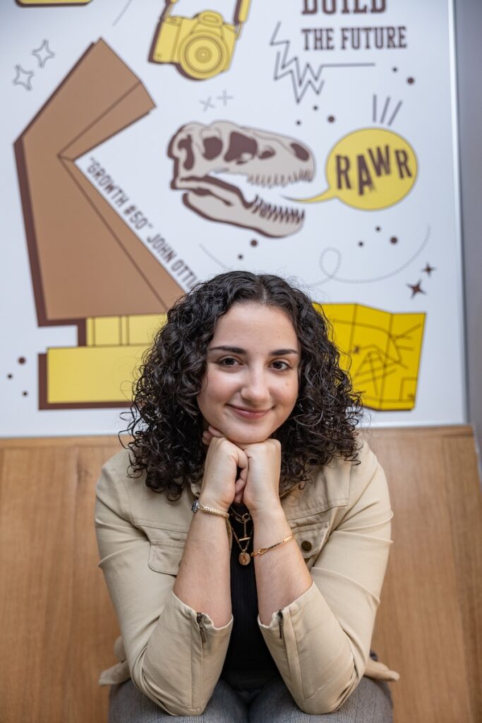 A portrait of alumna Julianna in front of her mural.