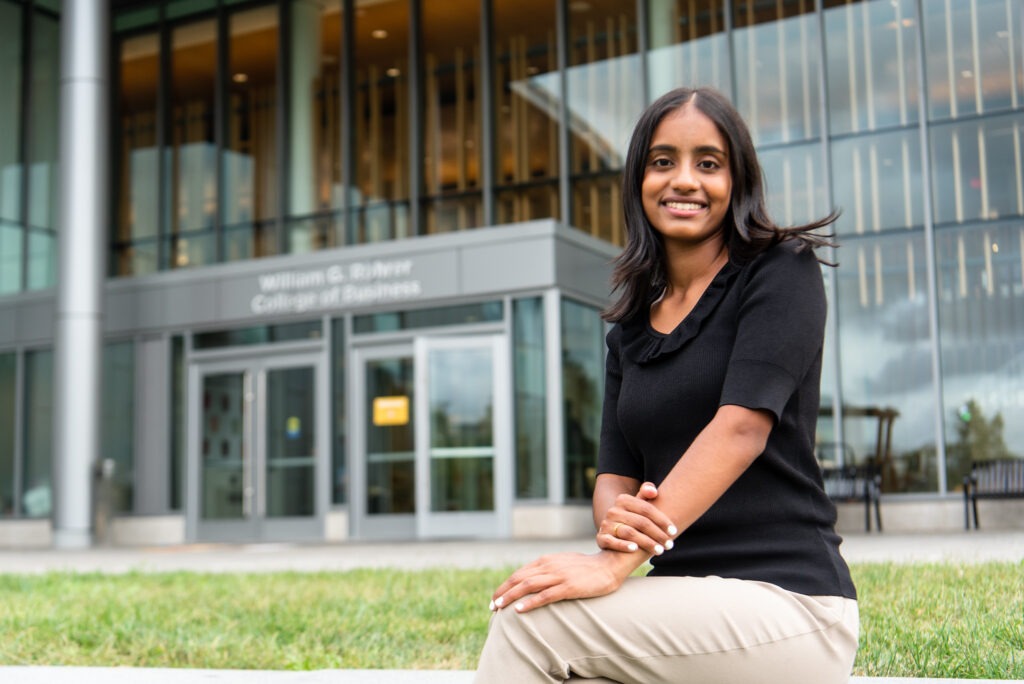 MBA student sitting outside a business school building, representing leadership development and MBA concentrations.