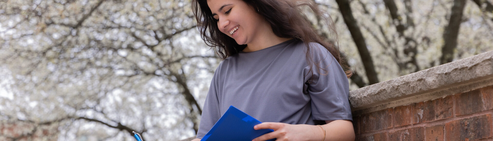 Woman sitting outside with blue folder and notepad reviewing MBA coursework while planning career growth.